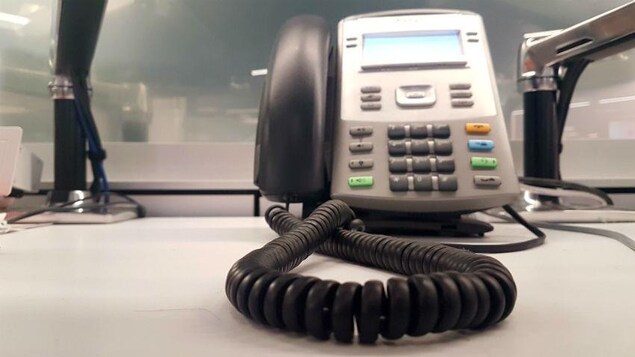 Un téléphone filaire devant un paravent.