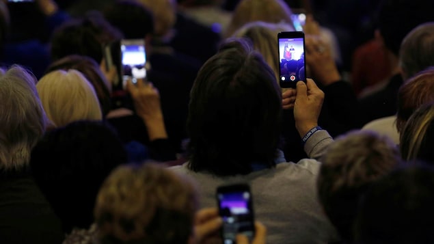 Des participants à un rassemblement du candidat François Fillon en France prennent des images avec leur téléphone.