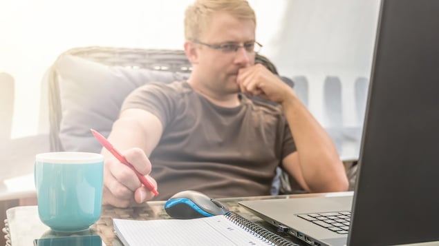 Un homme dans son bureau, à la maison. Il travaille sur son ordinateur portable.