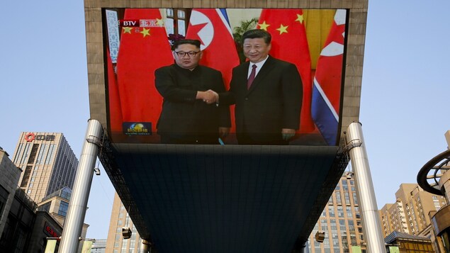 Un écran extérieur montre la rencontre entre le leader nord-coréen Kim Jong-un et le président chinois Xi Jinping. Un écran extérieur montre la rencontre entre le leader nord-coréen Kim Jong-un et le président chinois Xi Jinping.