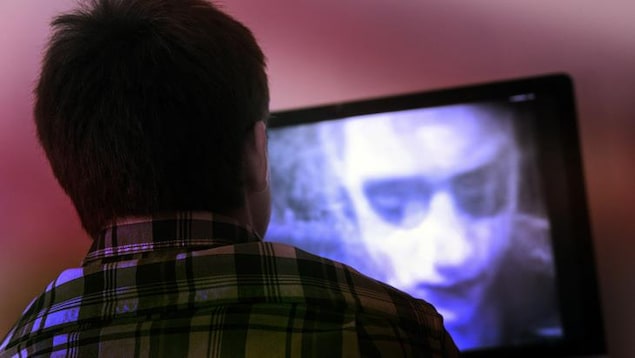 Un jeune homme regarde un film d'horreur à la télévision.