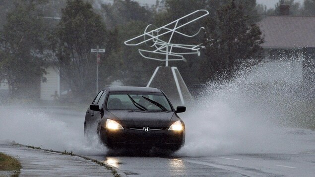 Une voiture roule dans une flaque d'eau durant une tempête.