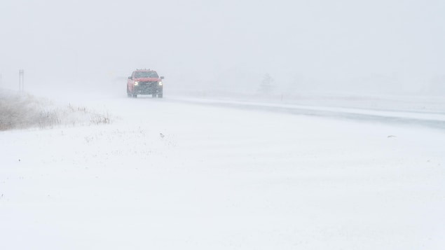 Un camion roule sur une route enneigée