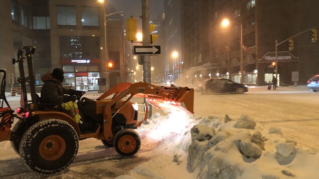 Au coin des rues Albert et O'Connor, un homme conduit un tracteur de déneigement sur le trottoir.