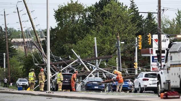 Des pompiers et des travailleurs des services publics constate les dégâts après le passage d'une tempête, à Ottawa. 