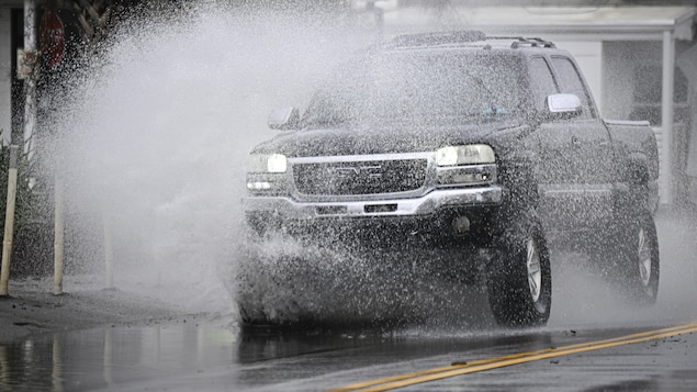 Un véhicule traverse une rue inondée.