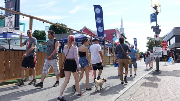 Des passants sur la rue piétonne bordée de terrasses.