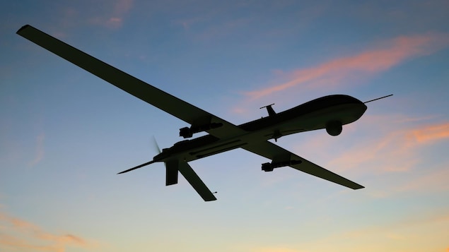 Une photo d'un drone militaire en vol prise au crépuscule.