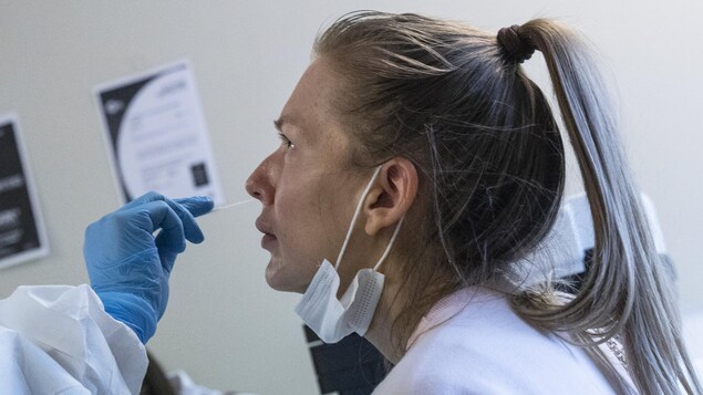 Une travailleuse de la santé prélève un échantillon d'une narine d'une femme le 7 août 2020 à l'aéroport Vnukovo de Moscou, en Russie.
