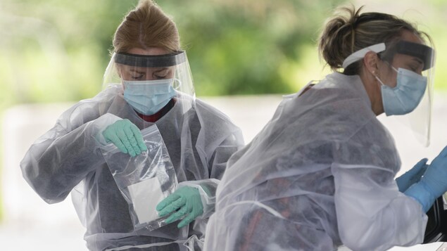 Une infirmière place un prélèvement dans un sac.