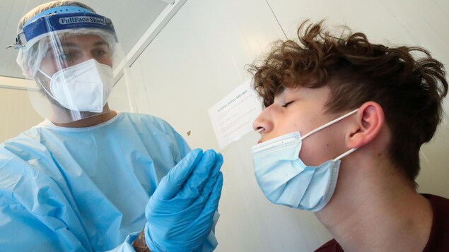 Une travailleuse de la santé récolte un échantillon de la narine d'un jeune homme pour un test de dépistage de COVID-19, le 28 avril 2021 à l'aéroport de Bruxelles, en Belgique.