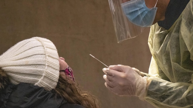 Une femme et un travailleur de la santé qui tient un écouvillon.