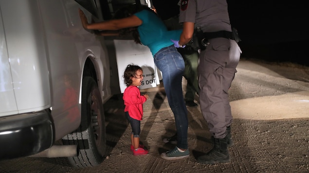 Une fillette pleure tandis que sa mère se fait fouiller par un agent de l'immigration. Une fillette pleure tandis que sa mère se fait fouiller par un agent de l'immigration.