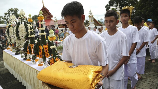 Les joueurs de l'équipe de soccer et leur entraîneur qui ont été rescapés d'une grotte en Thaïlande participent à une cérémonie bouddhiste