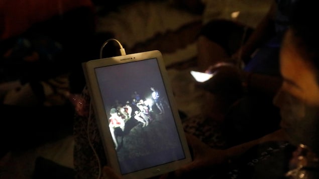 Une femme regarde une photo des jeunes sur une tablette électronique.