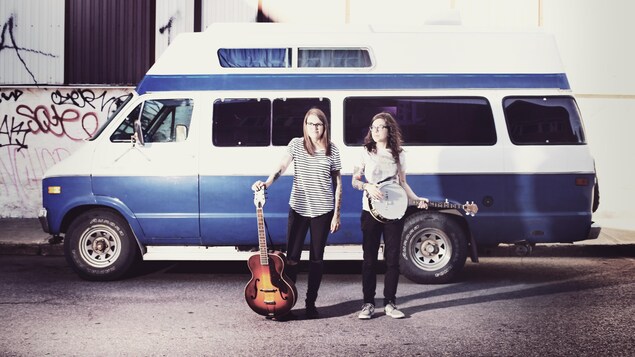 The Johans participera au Cabaret Festif, le 27 janvier. On aperçoit deux filles devant un westfalia. L'une tient une guitare et l'autre un banjo. The Johans participera au Cabaret Festif, le 27 janvier. On aperçoit deux filles devant un westfalia. L'une tient une guitare et l'autre un banjo.