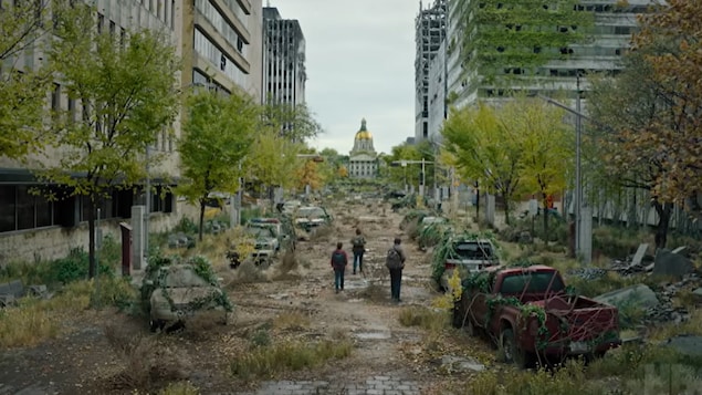 Trois personnes marchent dans une ville américaine post-apocalyptique. 
