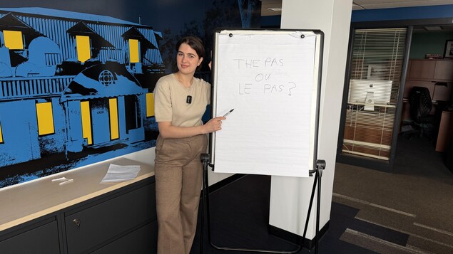 Gala Dionne pointe à l'écriture de The Pas sur un tableau.