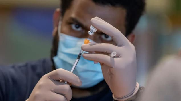 A male nurse prepares a dose of vaccine.
