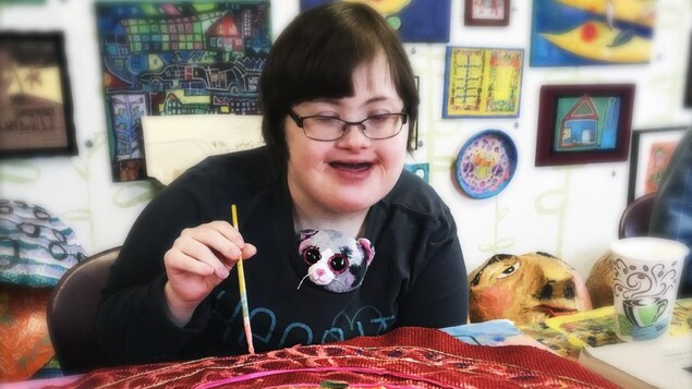 Une artiste assise à une table peint son oeuvre colorée. Une artiste assise à une table peint son oeuvre colorée.