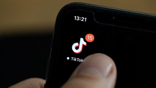 Un téléphone cellulaire où l'application TikTok affiche 15 notifications.