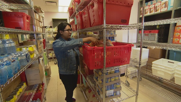A woman puts items in a basket in a storage area.