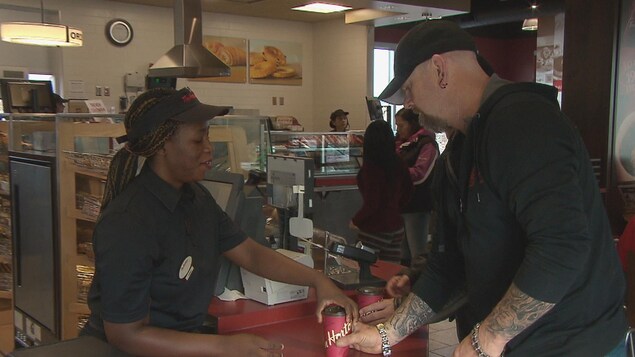 Un empleado sirve café a los clientes en una cafetería Tim Hortons de Moncton.