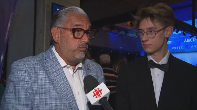 Deux hommes accordent une entrevue dans une salle de spectacle. 