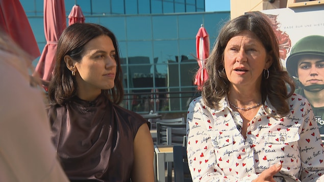 Deux femmes accordent une entrevue sur une terrasse, l'été. 