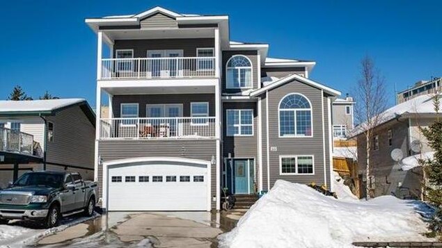 Une maison sur trois étages avec deux balcons et un garage.