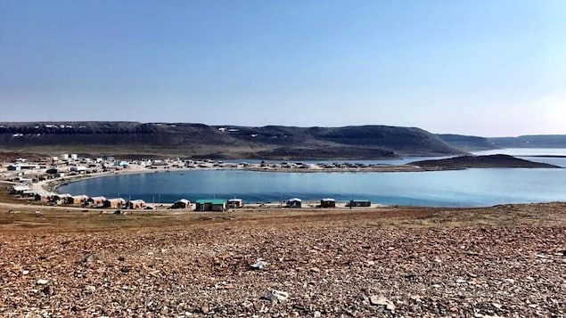 Maisons situées le long de la rive de l'océan Arctique, avec montagnes derrière, à Ulukhaktok, aux Territoires du Nord-Ouest.