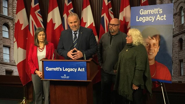 Todd Smith est derrière le lutrin lors de la conférence de presse à Queen's Park, entouré des autres participants Todd Smith est derrière le lutrin lors de la conférence de presse à Queen's Park, entouré des autres participants