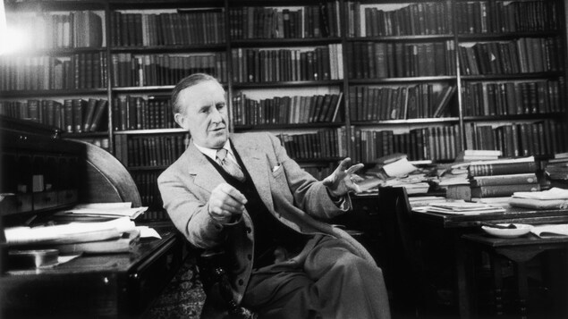 Portrait de l'auteur britannique J.R.R. Tolkien devant une bibliothèque remplie de livres.