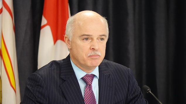 Tom Osborne est assis devant les drapeaux du Canada et de Terre-Neuve-et-Labrador.