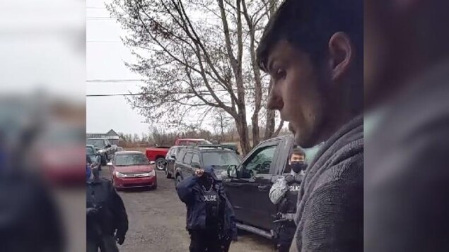 Un homme sans masque parle à des policiers masqués.