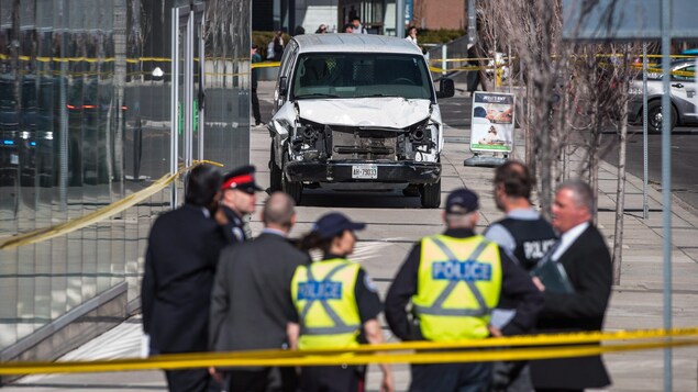 Un camion devant un immeuble et des policiers regroupés.