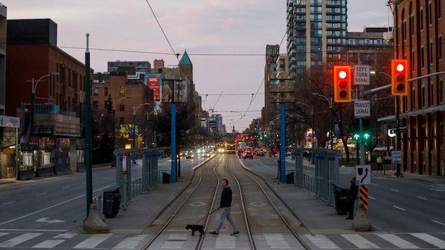 Un homme traverse une rue largement désertée de Toronto.