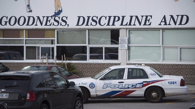 Une autopatrouille blanche, rouge et bleue devant un édifice en briques brunes