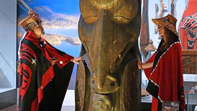 Dos miembros de la Primera Nación Nisga'a junto al tótem de la casa Ni'isjoohl en el Museo Nacional de Escocia.