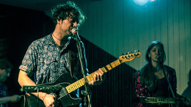 Trois musiciens se produisent sur scène. Trois musiciens se produisent sur scène.