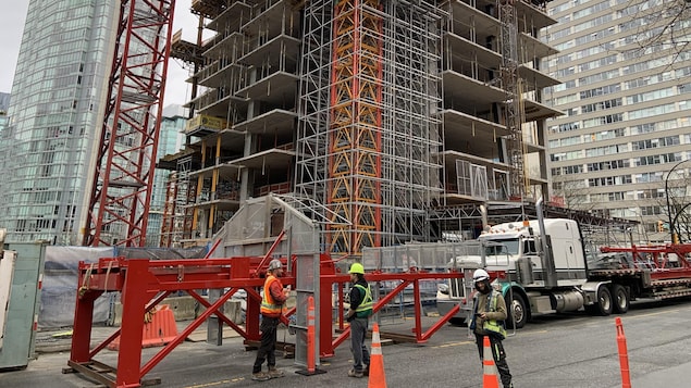 Des ouvriers sont en bas d'un immeuble en construction sur la rue Alberni à Vancouver.