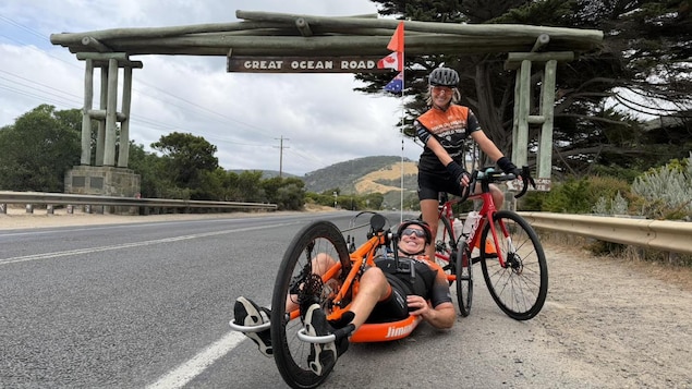 Un homme en vélo à main et une femme en bicyclette sourient sur le bord d'une route en Australie.