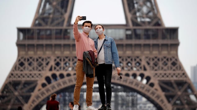 Un couple prend un autoportrait devant la tour Eiffel.