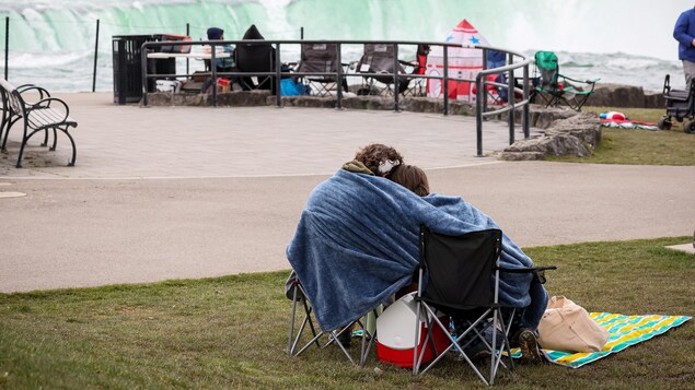 Des gens assis sur des chaises, devant les chutes Niagara.