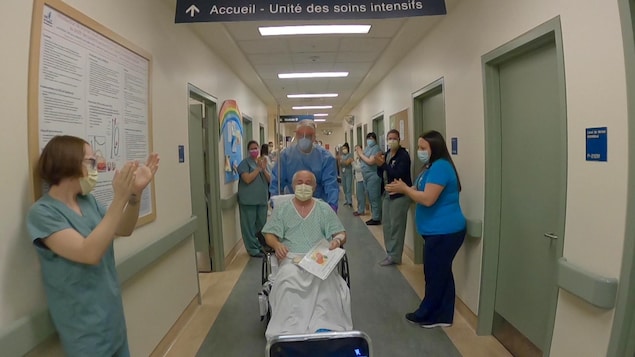 Des employés de l'hôpital applaudissent Daniel Bouchard alors qu'il obtient son congé de l'hôpital.