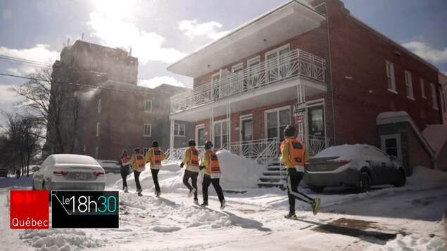 Des jeunes courent sur un trottoir, l'hiver.