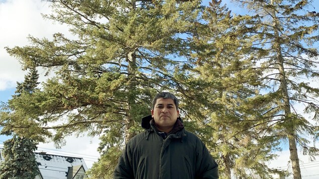 Portrait de Marcos Preciado Arroyo, travailleur agricole saisonnier, debout devant des arbres.