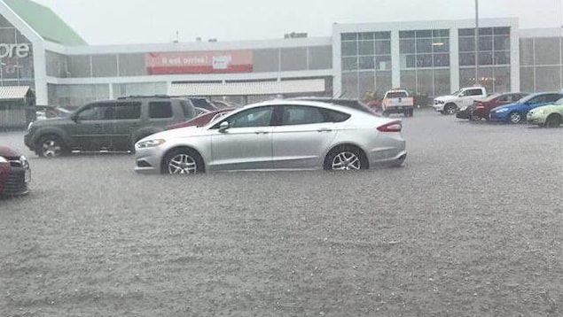 Des voitures sous la pluie garées devant le Superstore ont de l'eau jusqu'à la carrosserie. Des voitures sous la pluie garées devant le Superstore ont de l'eau jusqu'à la carrosserie.