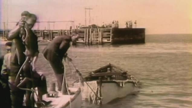 Photo d'archives d'hommes ramenant un bateau vide vers le quai.