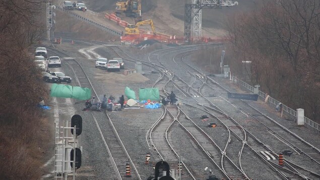 Un groupe de personnes semble camper sur des rails.